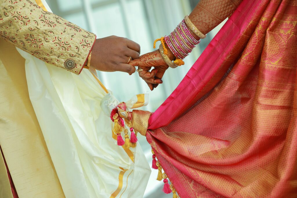 Elegant close-up of a couple holding hands in traditional attire during a wedding ceremony.